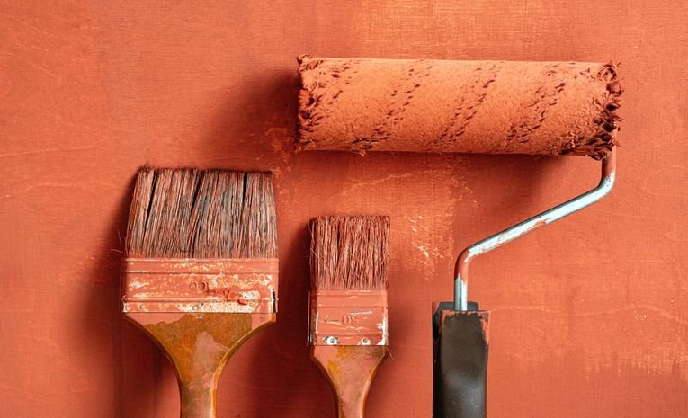 Freshly painted white skirting board with paintbrushes